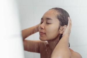 jeune femme se lavant les cheveux dans la douche. femme asiatique lavant ses cheveux noirs.