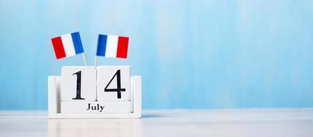 calendrier en bois du 14 juillet avec drapeaux français miniatures. fête nationale française, jour de la bastille et concepts de célébration heureuse photo