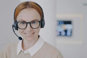 jeune femme consultante de centre d'appel. fille sympathique européenne dans le casque parlant au client en agence. photo