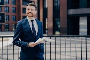 employé de bureau heureux en pause debout tout en tenant un journal photo