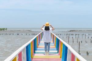 la vue arrière d'une femme asiatique debout et prenant une photo sur le pont arc-en-ciel pour voir le point de vue de la province de samut sakorn.