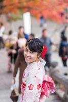 jeune femme touriste portant un kimono profitant de feuilles colorées dans le temple kiyomizu dera, kyoto, japon. fille asiatique avec une coiffure en vêtements traditionnels japonais en saison de feuillage d'automne photo