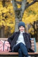 femme heureuse profiter du parc en plein air en automne, voyageur asiatique en manteau et chapeau sur fond de feuilles de ginkgo jaune photo