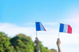 main tenant le drapeau de la france sur fond de ciel bleu. vacances de la fête nationale française, du jour de la bastille et des concepts de célébration heureuse photo