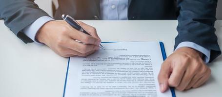 homme d'affaires signant des documents contractuels après lecture, homme tenant un stylo et approuvant le rapport d'activité. accord contractuel, partenariat et concepts d'accord photo