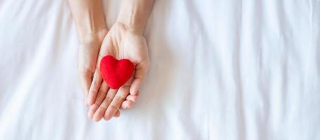 femme tenant en forme de coeur rouge sur fond blanc. soins de santé, assurance-vie, don, santé et concept de la journée mondiale du cœur photo