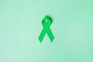 ruban vert sur fond de couleur verte pour soutenir les personnes vivant et malades. foie, vésicule biliaire cancer des voies biliaires et concept de mois de sensibilisation au don d'organes photo