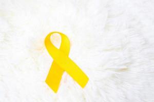 ruban jaune sur fond blanc pour soutenir les personnes vivant et malades. journée de prévention du suicide en septembre, mois de sensibilisation au cancer infantile et concept de journée mondiale contre le cancer photo