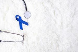 mars mois de sensibilisation au cancer colorectal, ruban bleu foncé avec stéthoscope sur fond blanc pour soutenir les personnes vivant et malades. soins de santé, espoir et concept de la journée mondiale du cancer photo
