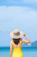 femme touriste en maillot de bain jaune et chapeau, voyageur heureux prenant un bain de soleil sur une plage paradisiaque sur les îles. destination, envie de voyager, voyage en asie, été tropical, vacances et concept de vacances