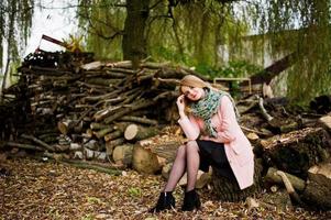 jeune fille blonde au manteau rose posé sur fond de souches de bois. photo