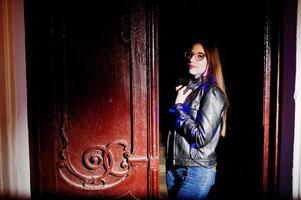 portrait de nuit d'une fille modèle portant des lunettes, un jean et une veste en cuir, avec une guirlande bleue sur elle. photo