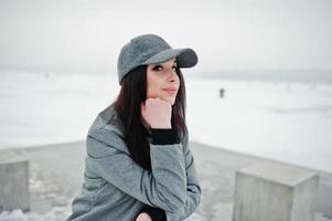 fille brune élégante en casquette grise, style de rue décontracté le jour de l'hiver. photo