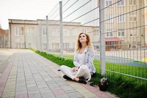 fille modèle blonde bouclée élégante porter sur blanc posant contre la clôture. photo