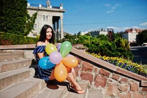 magnifique fille brune dans la rue de la ville avec des ballons à portée de main. photo