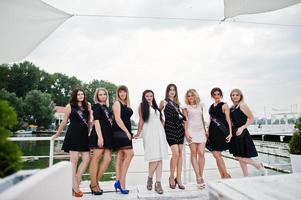 groupe de 8 filles portant du noir et 2 mariées à la fête de poule s'amusant à la jetée du côté de la plage. photo