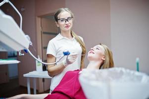 femme dentiste dans des verres spéciaux traitant les dents de son patient avec des instruments dentaires. photo