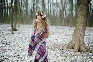 bouclée jolie fille blonde avec couronne en plaid à carreaux à la forêt enneigée en hiver. photo