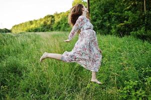 portrait d'une superbe jeune fille en robe sautant sur le pré. photo