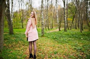 jeune fille blonde au manteau rose posé sur le parc d'automne. photo