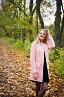 jeune fille blonde au manteau rose posé sur le parc d'automne. photo