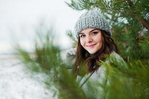 portrait d'une fille douce en manteau gris et chapeau contre l'arbre du nouvel an en plein air. photo