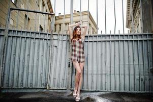 étonnantes longues jambes avec des talons hauts fille portent un chapeau contre une clôture en fer. photo