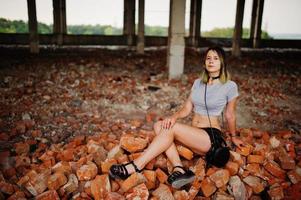 vêtements de fille sur des shorts à une usine abandonnée assise sur de la brique. photo