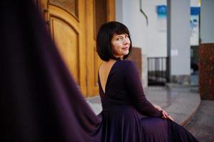 femme brune adulte à fond de robe violette vieilles portes en bois. photo