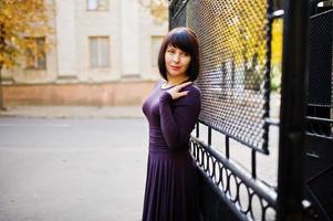 femme brune adulte à fond de robe violette portes de fer noir. photo