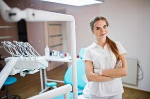 belle dentiste féminine posant en blouse blanche dans une armoire moderne bien équipée. photo