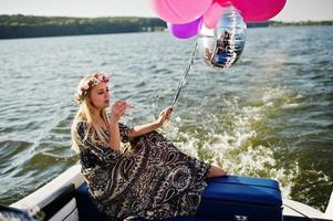 fille blonde en couronne assise sur un yacht à la fête de poule avec champagne. photo