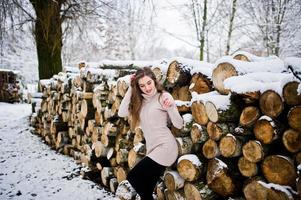 belle fille brune en vêtements chauds d'hiver. modèle sur pull d'hiver près de la souche. photo