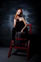 modèle de mode fille aux cheveux rouges avec à l'origine maquillage comme prédateur de léopard contre le mur d'acier. portrait en studio sur échelle. photo