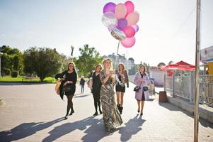 cinq filles portent du noir marchant avec des ballons à la fête de poule. photo