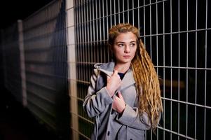 fille avec des dreadlocks marchant dans la rue de nuit de la ville. photo