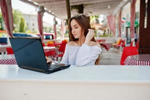 portrait d'une femme d'affaires indépendante forte et prospère portant des vêtements et des lunettes décontractés intelligents travaillant sur un ordinateur portable dans un café. photo