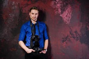 portrait en studio d'un photographe professionnel élégant avec appareil photo, porter une chemise bleue et une cravate. photo