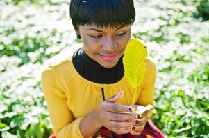 fille afro-américaine en robe jaune et rouge au parc d'automne automne. photo