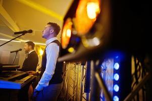 groupe de musique musical live se produisant sur une scène avec différentes lumières. jeu du claviériste. photo