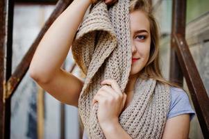 jeune fille blonde en jupe noire avec foulard posé dans la rue de la ville près de l'armure de fer. photo