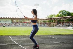 portrait d'une jeune femme heureuse en tenue de sport faisant des exercices avec une corde à sauter. photo