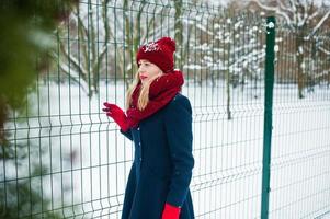 fille blonde en écharpe rouge et manteau marchant au parc le jour de l'hiver. photo