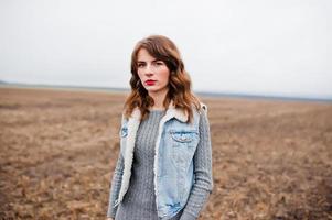 portrait de fille brune bouclée en veste de jeans sur le terrain. photo