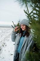 portrait d'une fille douce en manteau gris et chapeau contre l'arbre du nouvel an en plein air. photo