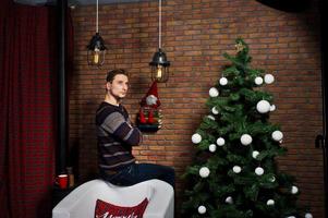 portrait en studio d'homme contre l'arbre de noël avec des décorations. photo