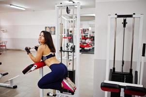 belle jeune femme faisant des exercices et travaillant dur dans la salle de gym et appréciant son processus d'entraînement. photo