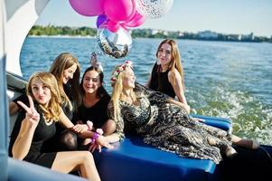 cinq filles portent du noir s'amusant au yacht contre le lac à la fête de poule. photo