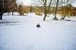 jolie petite fille avec des traîneaux de soucoupe à l'extérieur le jour de l'hiver. photo