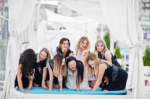 groupe de 8 filles portant du noir et 2 mariées à la fête de poule s'amusant à la jetée du côté de la plage. photo